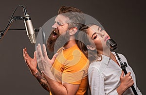 Singer couple singing rock. Sound producer recording song in a music studio. Excited duet Karaoke.