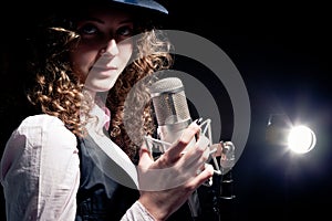 Singer in hat with microphone on the black