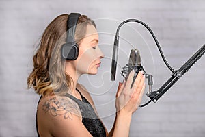 Singer pop or rock music with a tattoo, works with a studio microphone, sings