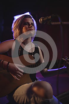 Singer practicing with guitar in nightclub