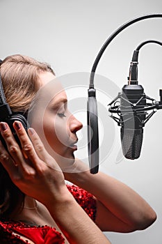 Singer or radio host working in a recording studio with a microphone in headphones close-up, blogging, radio, recording an album