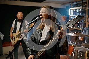 Singer singing in microphone playing guitar, repetition of rock band in garage