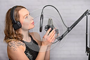 Singer with a tattoo sings rock music in the studio into a microphone, musician and treble vocals