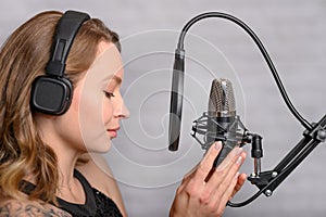Singer with a tattoo sings rock music in the studio into a microphone, musician and treble vocals photo