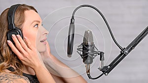 Singer with a tattoo sings rock music in the studio into a microphone, musician and treble vocals photo