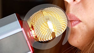 Singer woman sings a song in a recording studio. Close up of the mouth of the singer with microphone