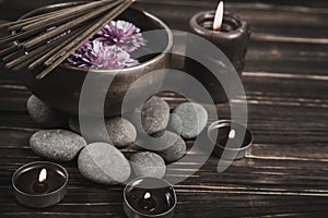 Singing bowl with candles with pebbles on dark wooden background