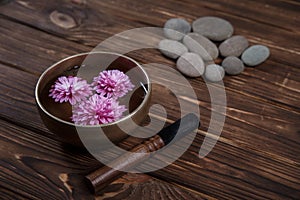 Singing bowl with candles with pebbles on dark wooden background