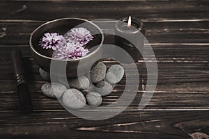 Singing bowl with candles with pebbles on dark wooden background