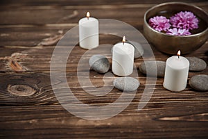 Singing bowl with candles with pebbles on dark wooden background