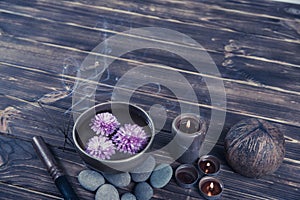 Singing bowl with candles with pebbles on dark wooden background