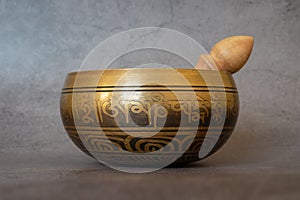 Singing bowl close-up, soothing and meditative. Singing bowl with sanskrit engraving pattern and wooden mallet  on gray