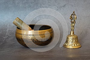 Singing bowl and golden bell close-up, soothing and meditative. Singing bowl with sanskrit engraving pattern and wooden mallet and