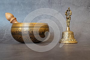 Singing bowl and golden bell close-up, soothing and meditative. Singing bowl with sanskrit engraving pattern and wooden mallet and