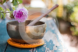 Singing bowl on a rustic wooden table with flowers, zen, outdoors