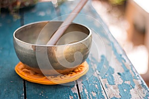 Singing bowl on a rustic wooden table with flowers, zen, outdoors