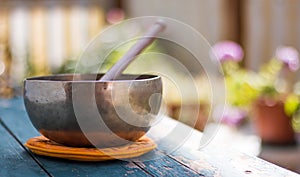 Singing bowl on a rustic wooden table with flowers, zen, outdoors photo