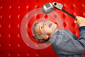 Singing boy with microphone on rack against wall