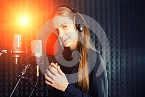 Singing girl sing to the professional microphone in the record studio. Process of create a new hit song by young singer