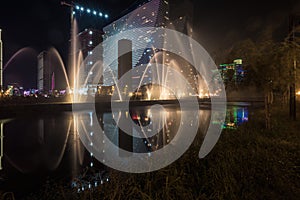 Singing light and music fountain on background of panorama of beautiful buildings at night