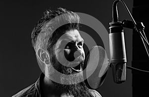 Singing man in a recording studio. Expressive bearded man with microphone. Closeup portrait.