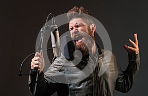 Singing man in a recording studio. Expressive bearded man with microphone. Expressive singer with microphone.