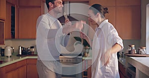 Singing, play or happy couple in home kitchen bonding together for fun freedom on holiday vacation. Cooking meal, woman