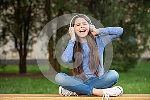 Singing song. Teen girl singing song listening to music in headphones outdoors, singing