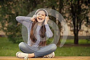 Singing song. Teen girl singing song listening to music in headphones outdoors, singing