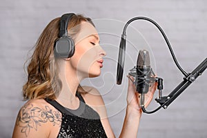 Singing and working in a studio with a microphone. A girl sings, rehearses in a recording studio