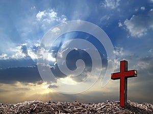 single antique red wooden cross on grave hill with sunray through clouds on dramatic sunrise sky