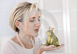 Single attractive older woman with a frog king in her hands.