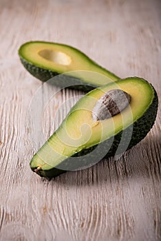 Single avocado severed in half on white wooden board