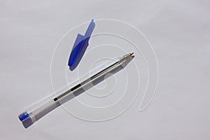 Single ballpoint pen with a letter cap on a brown background. View from above. The case handles white, caps blue. Education.