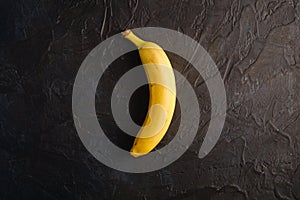 Single banana fruit on dark textured background