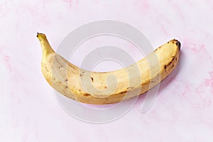 Single banana on a pink marble table
