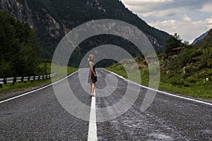 Single barefoot woman is walking along the mountain road. Travel, tourism and people concept