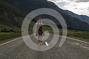 Single barefoot woman is walking along the mountain road. Travel, tourism and people concept