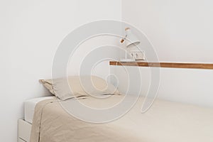 Single bed near wall shelf with night lamp in white bedroom