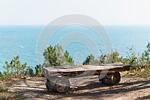 A single bench made of natural wood in the forest with a view of the sea