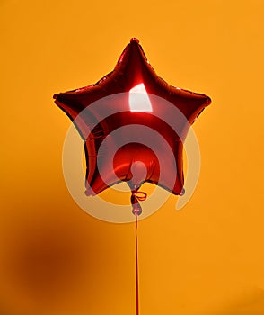 Single big red star balloon ballon object for birthday party on yellow