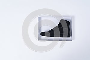 Single black leather boot in shoe box on white background.