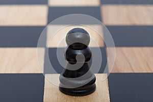 Single black wooden pawn on a white ssquare