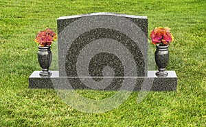 Single blank tombstone in cemetery with flowers