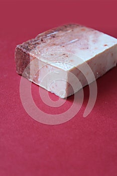 Single block of home made soap on dark red background