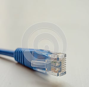Single blue RJ45 CAT6 shielded network data internet cable connector on gray background with copyspace.