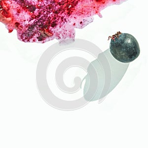 Single blueberry with bright red berry juice splatter on white background