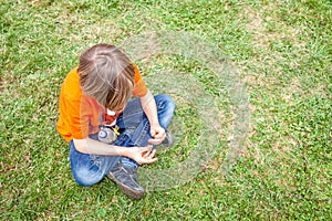 Single bored teen boy sitting on grass