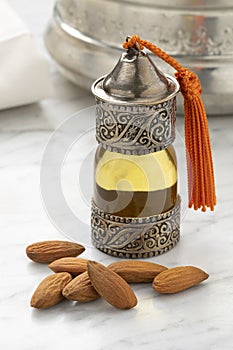 Single bottle with Moroccan almond oil and a heap of almonds in hamam