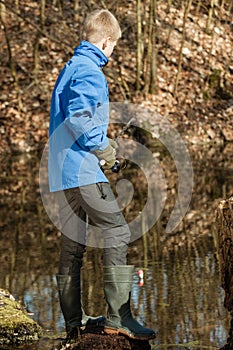 Single boy in blue jacket at pond fishing alone